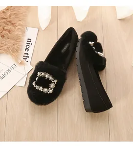 Close-up of black suede loafers featuring a sparkling pearl buckle and warm fur lining