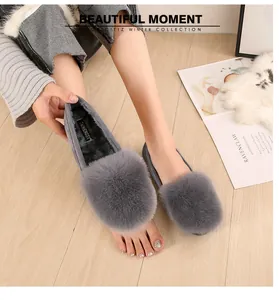 Detail showing grey faux fur loafers with warm black lining on light wood flooring