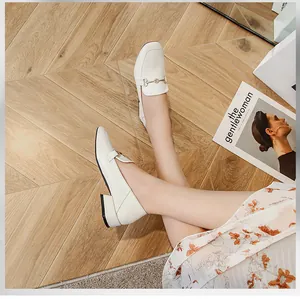 Gros plan de mocassins blancs à bout carré avec boucle mors dorée sur bois