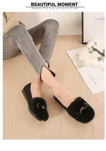 Detail of black plush flat loafers featuring warm faux fur and a golden metal buckle