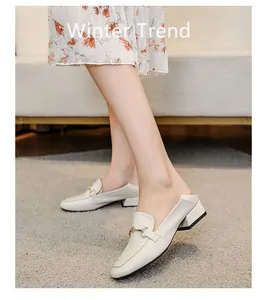 Détail de mocassins blanc cassé avec boucle dorée et petit talon carré sur mannequin