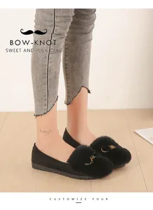 Detailed macro view of black faux fur loafers with gold metal letter accents and flat soles