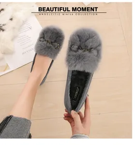 Detail of grey rabbit fur loafers with metal bow and plush interior on wood background