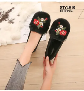 Détail de chaussures plates en fausse fourrure noire avec broderie florale et doublure douce
