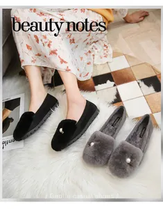 Detalle de mocasines de terciopelo con pompones de piel sintética y perla decorativa
