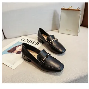 Détail de mocassin noir à bout carré avec boucle dorée et talon bloc stable et élégant