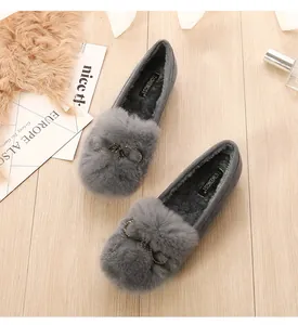 Close-up of gray faux fur flat shoes with rhinestone horseshoe buckle on wood floor