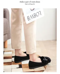 Detail of black faux fur pompom and metal bow on warm suede loafers for women