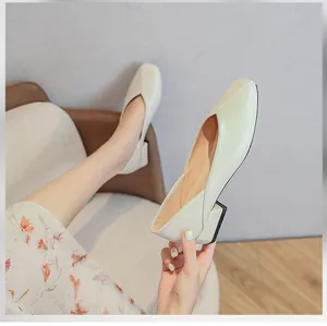 Close-up of cream square toe loafers with black block heels on a model in a cozy setting