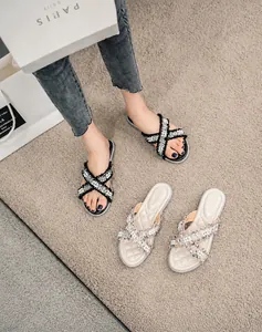 Dettaglio di sandali in tweed con perle, cinturini incrociati e plantare trapuntato