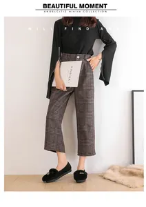 Detalle de pantalones anchos a cuadros marrones y top negro con cremallera para invierno