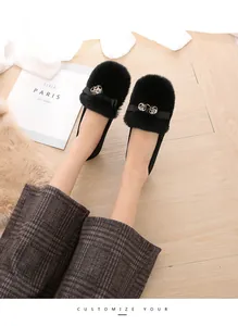 Detalle de mocasines de pelo sintético negro con lazo delicado y hebilla de esfera metálica