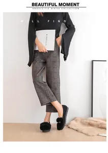 Detail van zwarte pluche loafers voor dames met een grijze geruite pantalon met wijde pijpen