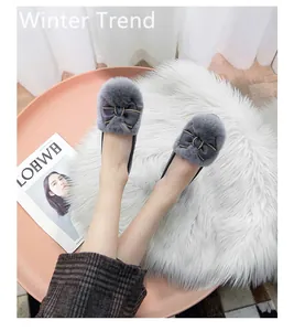 Close-up of grey plush winter loafers with elegant ribbon bow and gold chain detail