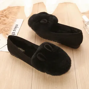 Mocasines negros de pelo de conejo con orejas lindas sobre suelo de madera