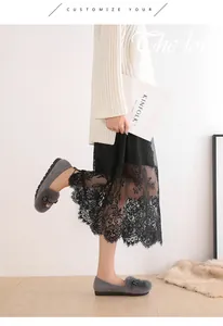 Detalle de mocasines de ante gris con ribete de piel y lazo sobre una alfombra de pelo