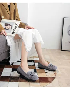 Detail of grey suede loafers with plush faux fur collar and metal bow decoration
