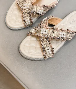 Dettaglio del cinturino in tweed con perle e plantare trapuntato su sandali da donna