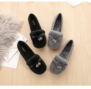 Detalle de mocasines de invierno cálidos con piel sintética y lazo en suelo de madera
