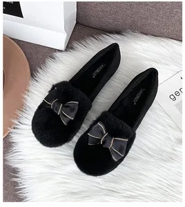 Detailed top view of black plush loafers featuring a silk bow and golden chain trim