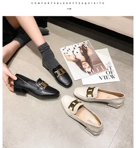 Close-up of black and beige loafer shoes with gold chain buckles on square-toed block heels