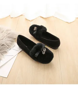 Detalle de mocasines de ante negro con pompones de pelo y lazos con anillas metálicas