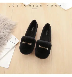 Detail van zwarte pluche loafers met bontafwerking en een gouden strik accessoire