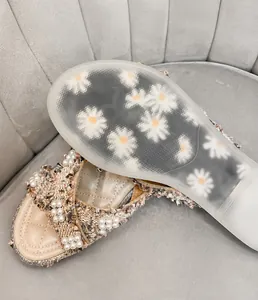 Dettaglio suola in gomma trasparente con motivo a margherita per sandalo beige