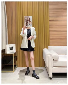 Damen-Outfit mit weißem Blazer, schwarzem Faltenrock und klassischen Loafers