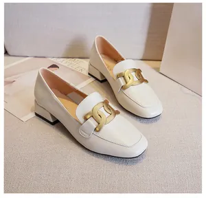 Detail of off-white loafers with gold chain buckle and square toe on textured background