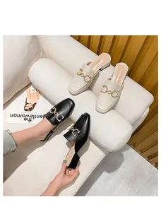 Detail of elegant pointed-toe mule heels with metallic horsebit buckles in beige and black