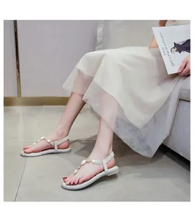 Detailansicht flacher beige T-Steg Sandalen mit Perlenbesatz und silbernen Glitzerelementen