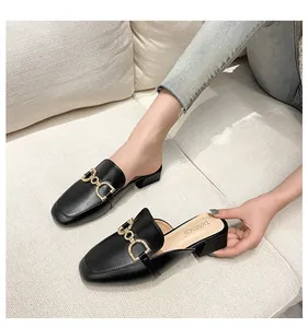 Detail shot of black leather mule sandals featuring a sparkling gold horsebit buckle