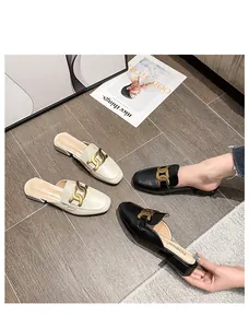 Detailaufnahme flacher Pantoletten mit goldenen Metallketten in Schwarz und Beige