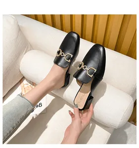 Detail of black leather mule with square toe and sparkling rhinestone horsebit buckle