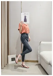 Flache Zehentrenner mit Perlen und Edelsteinen zu Jeans in einem modernen Wohnzimmer