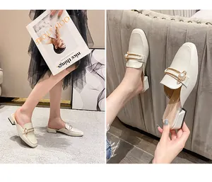 Detalle de elegantes mules crema con punta cuadrada y decoración de perla dorada