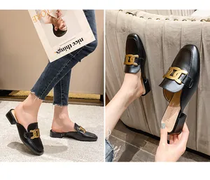 Details schwarzer Leder-Mules mit goldener Kettenschnalle und bequeme klobige niedrige Ferse