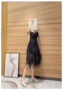 Detail of a black short-sleeve dress featuring a tiered mesh skirt and drawstring neckline