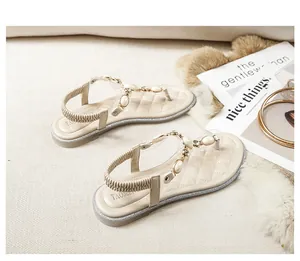 Details flacher beiger Sandalen mit transparenten Riemen, großen Perlen und glitzernden Strass