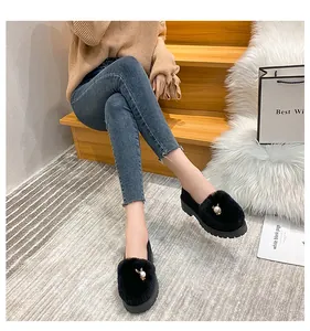 Détail de mocassins noirs en peluche avec breloque lapin en perle et semelle épaisse