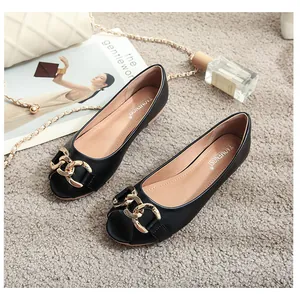 Flat black peep toe shoes with bold gold metal chain on elegant plush grey carpet background
