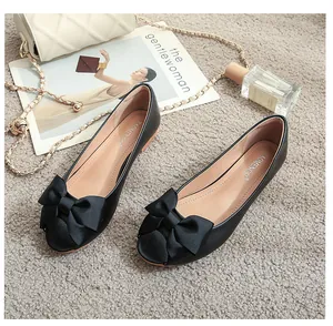 Flache schwarze Lederschuhe für Damen mit zarter Ripsbandschleife auf texturiertem Teppich
