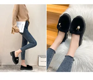 Détail de mocassins en peluche noire avec perles blanches et semelle épaisse en caoutchouc