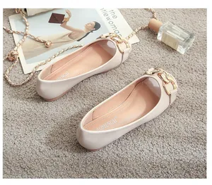 Flat beige loafers with golden chain detail, displayed with fashion accessories