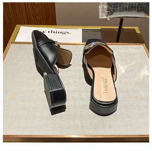 Detail of black square-toe mule featuring a luxury rhinestone buckle and low block heel