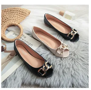 Close-up of stylish peep-toe flat shoes with gold chain buckle in black and beige
