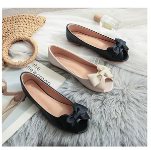 Nahaufnahme eleganter flacher Peep-Toe-Schuhe mit großen Schleifen auf weichem Plüsch