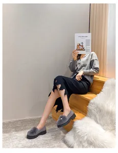 Mocassins à plateforme en daim gris avec pompon en fourrure et perle sur un escalier