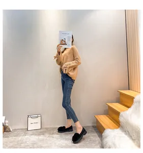 Herbstlook mit kamelfarbenem Schleifenpullover, Slim Jeans und Pelz-Loafer auf Teppich